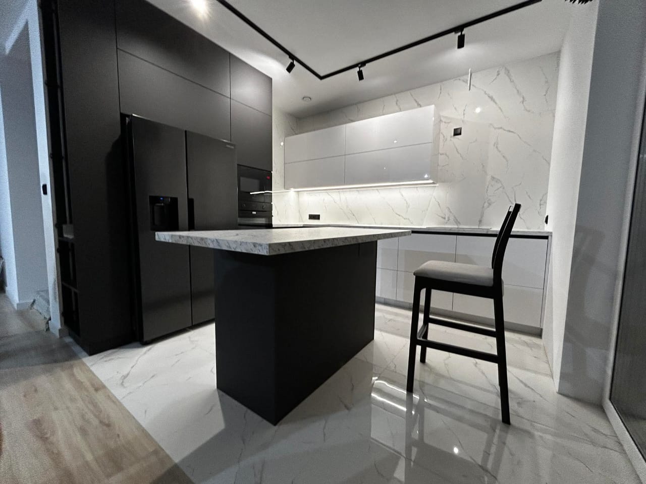 Cuisine noire avec îlot central, vue d'ensemble, réalisée par RSS Studio